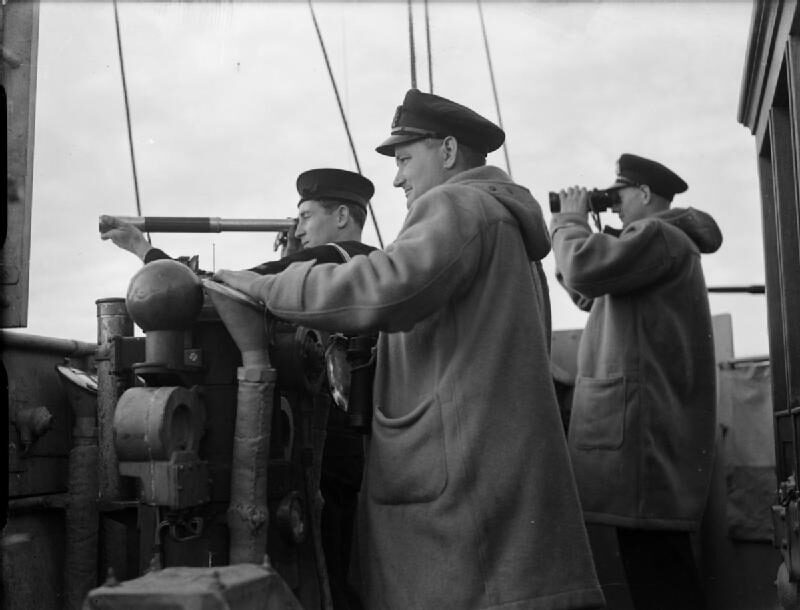 On a corvette's open bridge, a signalman sights along a telescope while two officers in duffel coats keep watch, one with binoculars